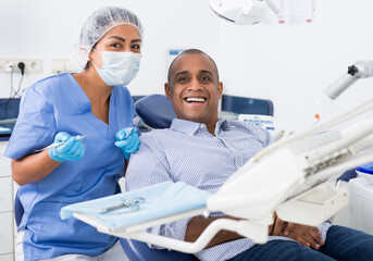 Happy man sitting in dental chair after teeth cure