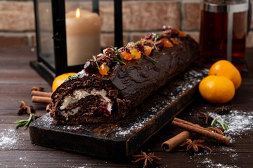 Christmas log rulate, dark christmas atmosphere with candles and mandarins around