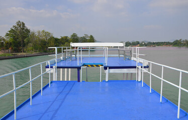 View from the deck of a ferry boat sailing on the river in the sunny summer day. Beautiful natural landscape in Thailand.