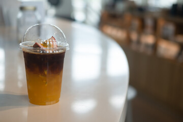 A plastic glass of Iced orange juice and passion fruit mix black cold brew coffee