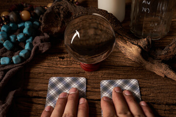 concept of fortune-telling on a wooden table and white candle with a crystal ball and tarot cards on dark background. hand                                                                    