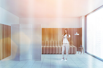 Young woman in white and wooden living room with sofa