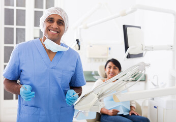 Obraz premium Portrait of positive dentist in dental office on the background of patient