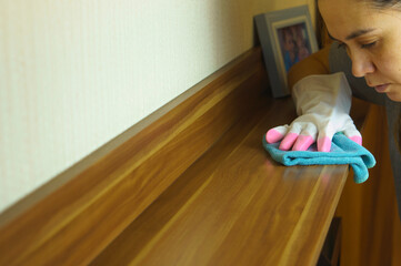 House cleaning, the concept of cleaning furniture from dust. A gloved hand is dusting the furniture in the house.