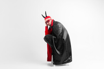 Caucasian male model in halloween black red costume and sunglasses with hat and horns posing over...