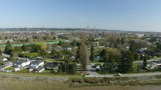 Flying upward with drone filming sprawling suburbia with highway and bridge in background near Surrey BC.
