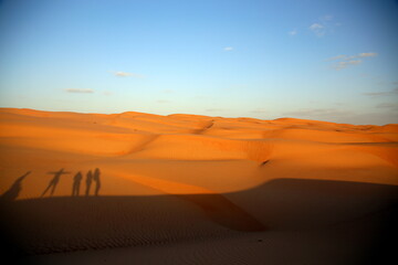 Shadows of people projected on the dunes by the light of the sunset, Wahiba Sands / Sharqiya Sands, Oman