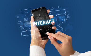 Female hand typing on smartphone with INTERACT inscription, social media concept