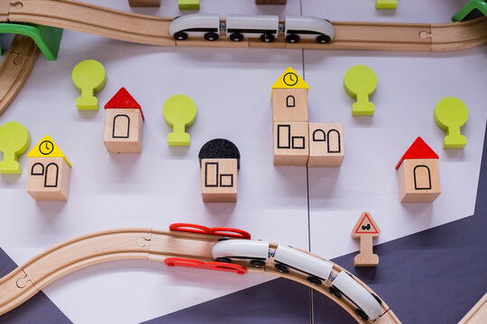 Toy wooden trains move on railways towards each other. Toys background.Houses, cars, and trees on bright background. Cityscape of toys.the development of imagination and children's games concept