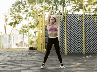 Fototapeta na wymiar Attractive slim fit woman trains on the sports ground. Healthy lifestyle
