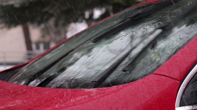 Snow faling on car front windshield. Wipers, wet windshield