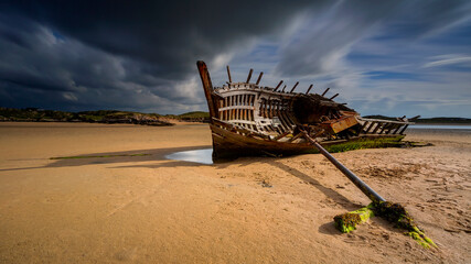 An old shipwreck boat abandoned stand on beach or Shipwrecked off the coast Bad Eddie Shipwreck - An old shipwreck found on the beach at Bunbeg, Donegal in Ireland.
