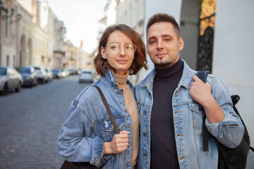 Charismatic smiling couple in denim jackets on urban street