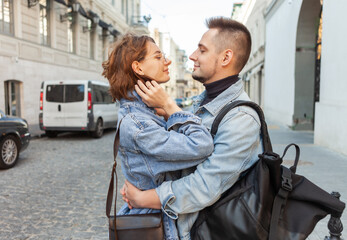 Charismatic smiling couple in denim jackets on urban street