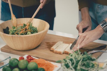 Woman and man couple family preparing vegetables to make healthy food salad in modern kitchen room