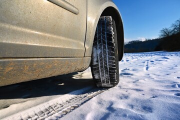 Car in winter in the snow. Winter tires. Winter landscape with sun and blue sky in the background.