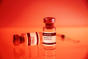Covid-19 vaccine bottle and syringe on a red background