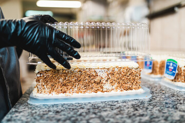 Confectioner packing deliciious cake in pastry shop. Sweets production and industry concept.