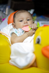 Fototapeta na wymiar 3-4 Month old baby girl sitting on a rubber duck floatie, Baby Girl Playing with floaties duck, child development