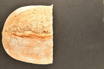 One half flavored loaf without yeast with bran flakes, close-up, on a slate board.