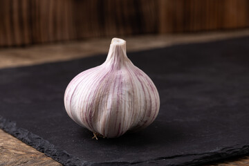 Unpeeled garlic bulb closeup on a black slate 