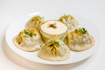 Delicious uzbek dumplings on a white plate. Manti with lamb meat. POV