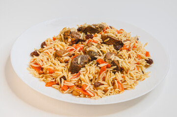 Fried lamb slices with rice. Fresh Uzbek pilaf on a white plate. POV