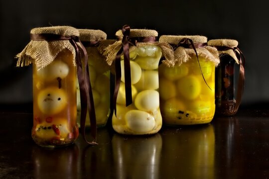 Jars of different types of pickled eggs on a dark wooden table 