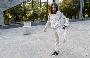 Fit brunette runner woman working out outdoors. Feminine sportswoman in sportswear practices stretching or warming up her arms before training. Healthy lifestyle