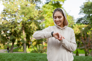 Fototapeta na wymiar Fit runner woman in sportswear looks at smart bracelet measuring the pulse outdoor