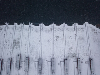 Snow-covered rails on the shore at a shipyard. Snowy day, blizzard. Aerial drone view.