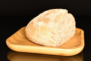 One half of a delicious loaf without yeast with bran cereal on bamboo dish, close-up, isolated on black.