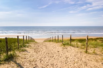 Fotobehang Noordzee, Nederland Een zandpad dat op een heldere herfstdag over een dijk naar de zee in nederland leidt