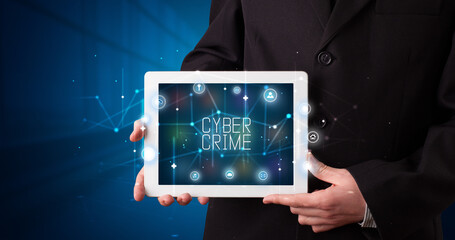 Young business person working on tablet and shows the digital sign: CYBER CRIME