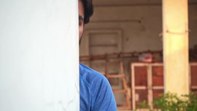 Indian Man Hiding And Peeking Out Behind The Wall Outdoor - close up