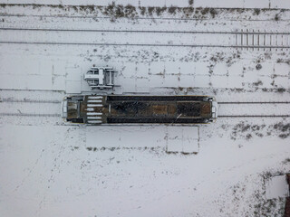Diesel locomotive covered with snow. Snowy day, blizzard. Aerial drone top view.