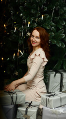 Obraz na płótnie Canvas the girl sits under the christmas tree and enjoys the gifts