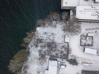 Electric pole on the snowy shore. Snowy day, blizzard. Aerial drone view.