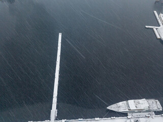 Snow-covered pier. Snowy day, blizzard. Aerial drone view.