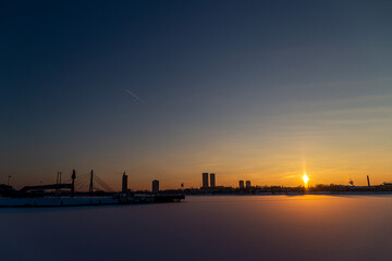 Sunset over the river on a cold winter day with the city in the background.