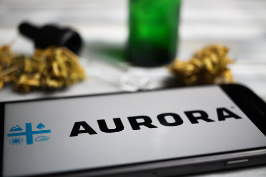 Viersen, Germany - January 9. 2021: Closeup of mobile phone screen with logo lettering of cannabinoid company aurora cannabis, blurred marijuana and pipette background
