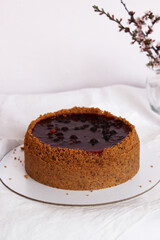 Homemade cheesecake drenched in currant jam and sprinkled with crumbs on a table covered with a white tablecloth. Selective focus.
