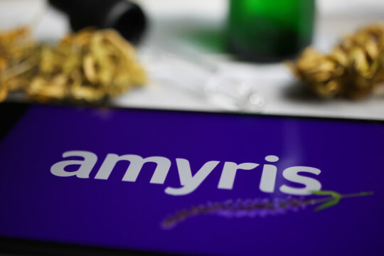 Viersen, Germany - January 9. 2021: Closeup of mobile phone screen with logo lettering of cannabinoid company amyris inc, blurred marijuana and pipette background