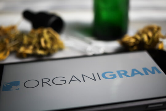 Viersen, Germany - January 9. 2021: Closeup of mobile phone screen with logo lettering of cannabinoid company Organigram holdings, blurred marijuana and pipette background
