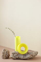 Geometric minimalist isometric composition with natural material stone and bright modern yellow shapes with dried floral branch, copy space, abstract design concept, vertical
