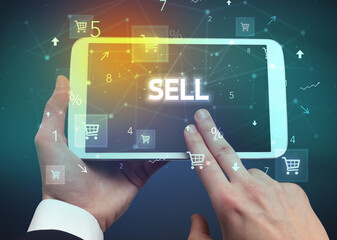 Close-up of a hand holding tablet with SELL inscription, online shopping concept