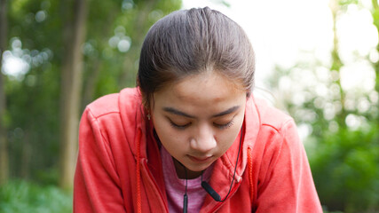 Asian women rest after running. wearing jacket and earphone