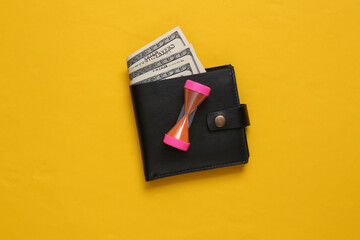 Time is money. Leather wallets with hourglass. on yellow background.