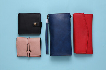 Different leather wallets on a light blue background. Top view - obrazy, fototapety, plakaty