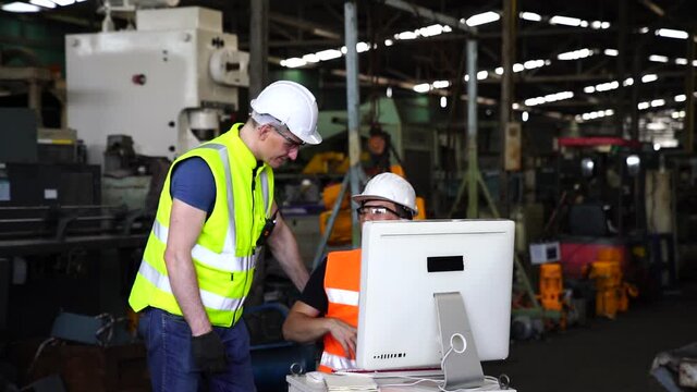 Manufacturing industry with technology. Engineers and technicians are working on industrial computers. Engineer manager command computer to produce products by automate machines in factory workshop.